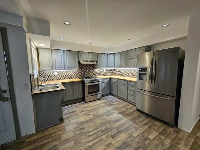 kitchen featuring gray cabinetry, sink, dark wood-type flooring, backsplash, and stainless steel appliances