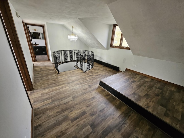 additional living space with hardwood / wood-style flooring, lofted ceiling, and an inviting chandelier