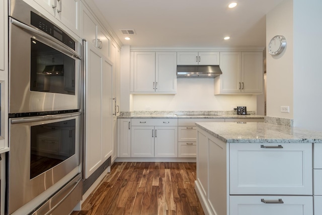 kitchen with white cabinetry, light stone counters, extractor fan, double oven, and dark wood-type flooring