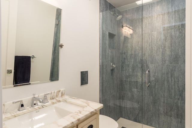 bathroom featuring toilet, vanity, and a shower with shower door