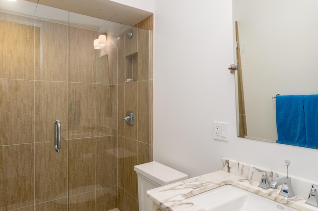 bathroom featuring toilet, a shower with shower door, and vanity