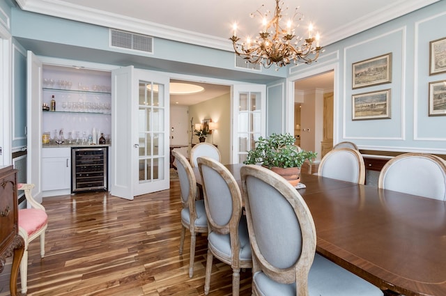 dining area with bar area, a notable chandelier, built in shelves, beverage cooler, and dark hardwood / wood-style flooring