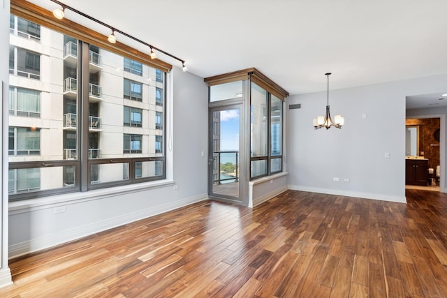 spare room featuring wood-type flooring, a chandelier, and rail lighting