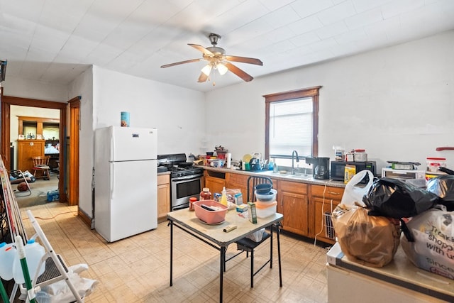 kitchen featuring sink, ceiling fan, white fridge, and stainless steel gas range oven