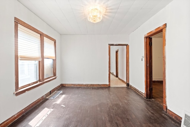 unfurnished room with an inviting chandelier and dark hardwood / wood-style floors