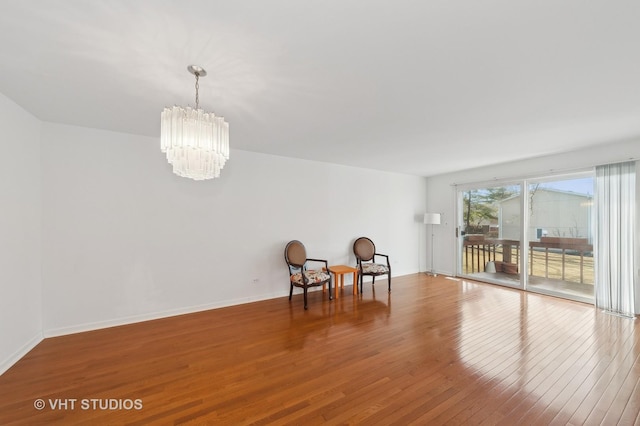 unfurnished room with wood-type flooring and an inviting chandelier