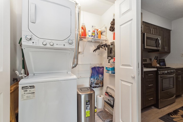 laundry room featuring stacked washer / drying machine, a textured ceiling, and light wood-type flooring