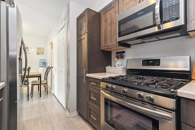 kitchen featuring stainless steel appliances, light hardwood / wood-style floors, and dark brown cabinets