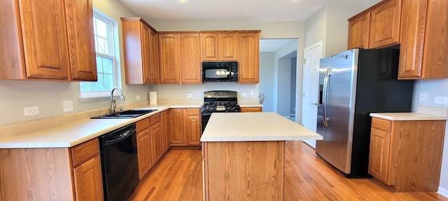 kitchen with sink, a kitchen island, black appliances, and light hardwood / wood-style floors