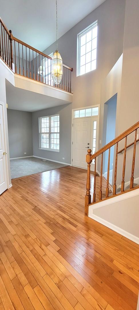 entryway featuring a towering ceiling, light wood-type flooring, and a notable chandelier