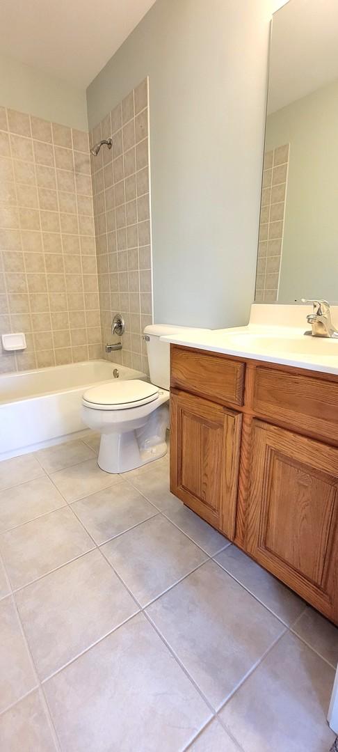 full bathroom with toilet, tile patterned flooring, tiled shower / bath, and vanity