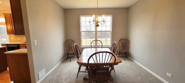 dining space with a chandelier and light colored carpet