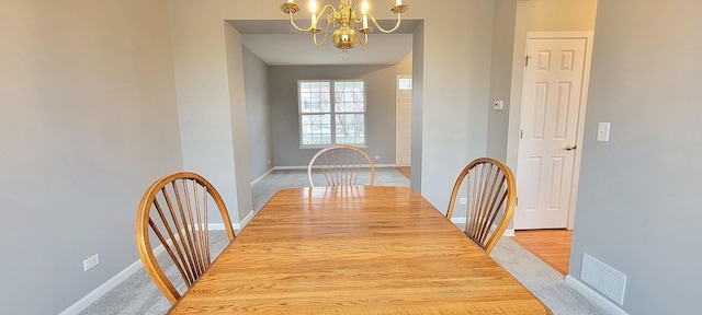 carpeted dining room with a notable chandelier