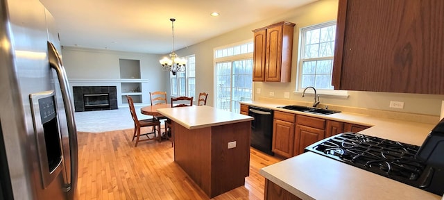 kitchen featuring a tiled fireplace, stainless steel fridge, a kitchen island, sink, and black dishwasher