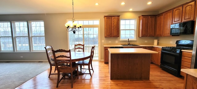 kitchen featuring a chandelier, black appliances, a center island, pendant lighting, and sink