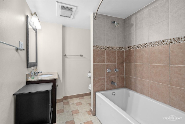 full bathroom featuring tiled shower / bath, vanity, and toilet