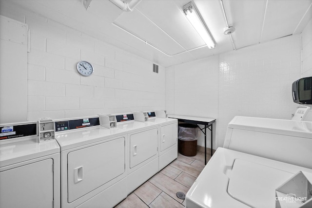 laundry area featuring tile walls and separate washer and dryer