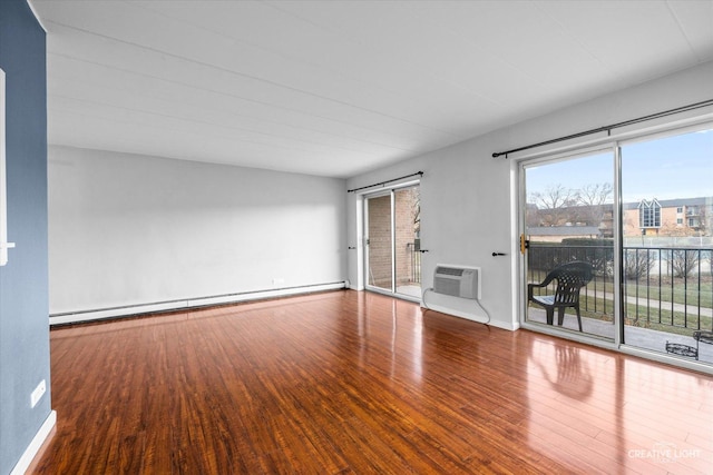 spare room featuring a baseboard heating unit, a wall mounted AC, a wealth of natural light, and hardwood / wood-style floors