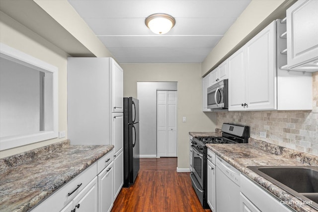 kitchen with stainless steel appliances, dark stone counters, dark hardwood / wood-style flooring, decorative backsplash, and white cabinets