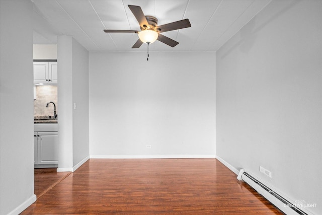 spare room with sink, a baseboard heating unit, ceiling fan, and dark wood-type flooring