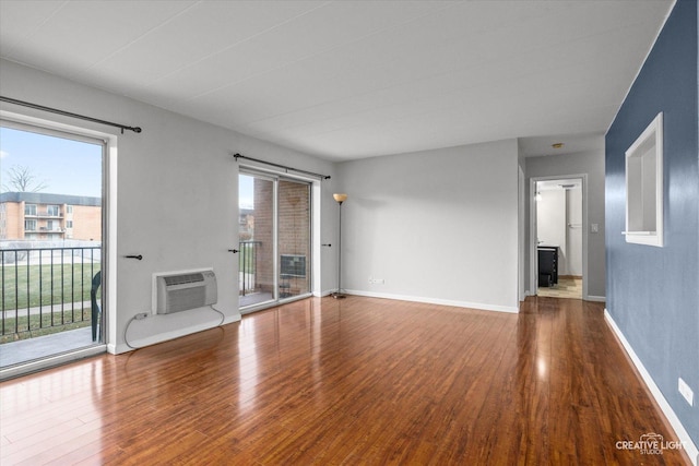 unfurnished living room with a wall mounted air conditioner and hardwood / wood-style flooring