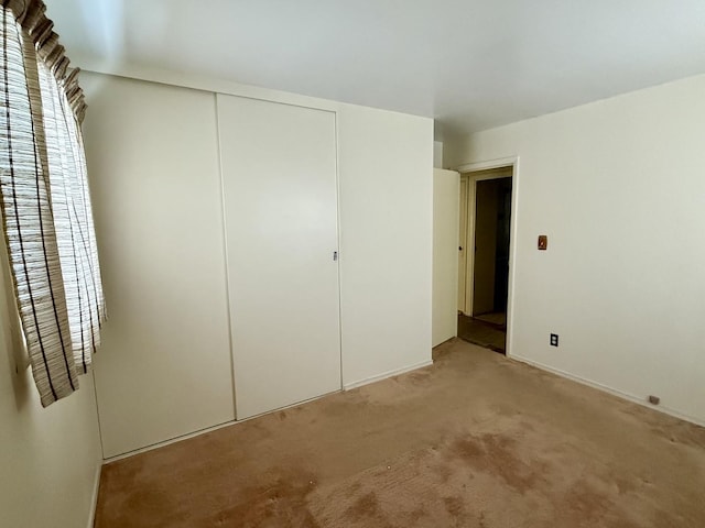 unfurnished bedroom with light carpet and a closet