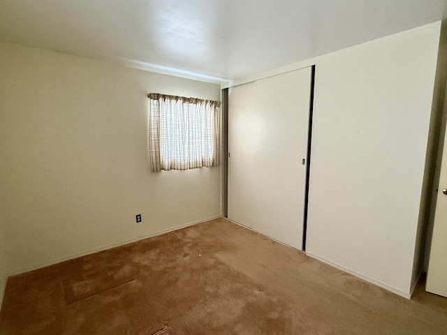 unfurnished bedroom featuring a closet and light colored carpet