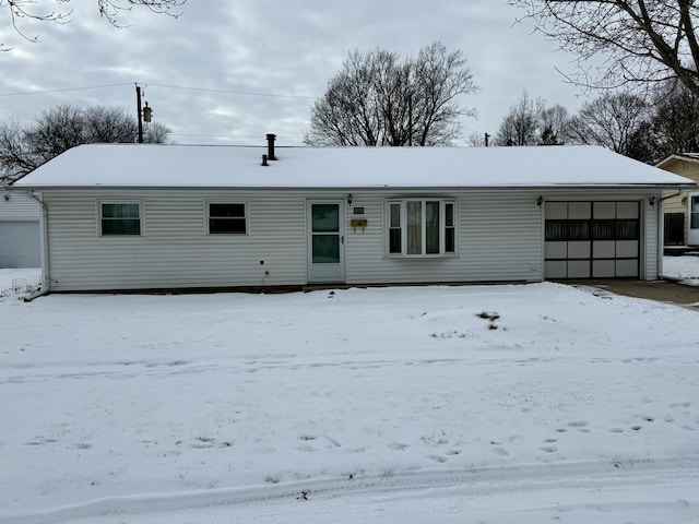 snow covered rear of property with a garage