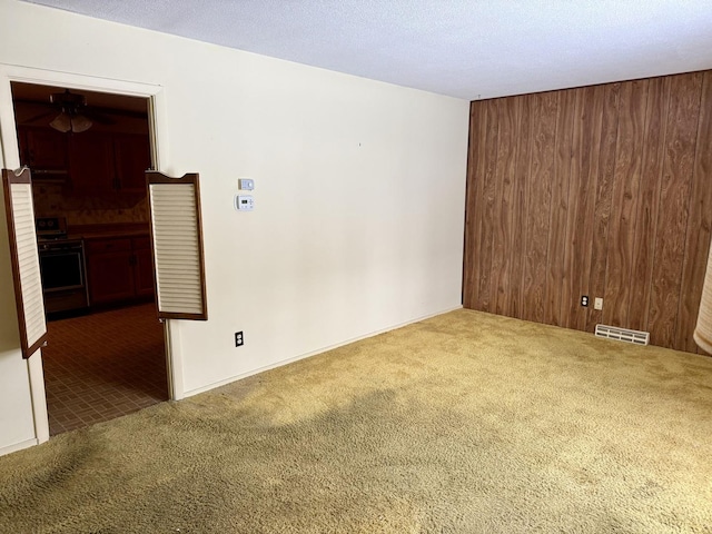 carpeted spare room with a textured ceiling and wood walls