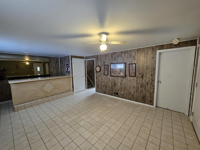 interior space featuring light tile patterned flooring, wood walls, and ceiling fan