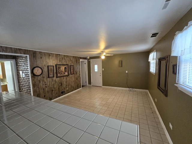 interior space featuring tile patterned flooring, wood walls, and ceiling fan