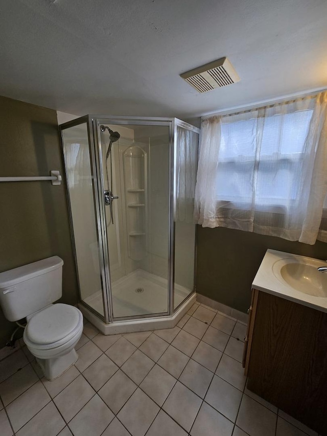 bathroom with tile patterned flooring, an enclosed shower, vanity, and toilet