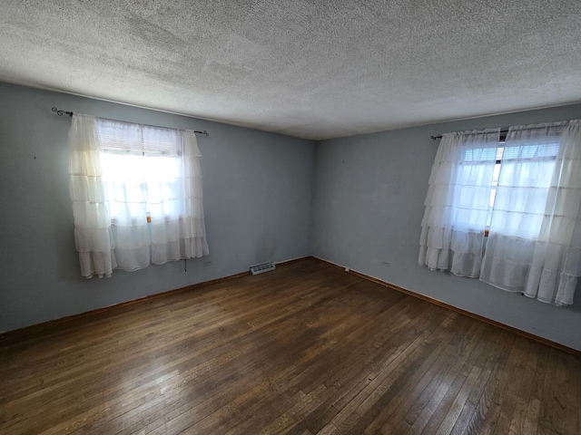 spare room with a textured ceiling and dark wood-type flooring