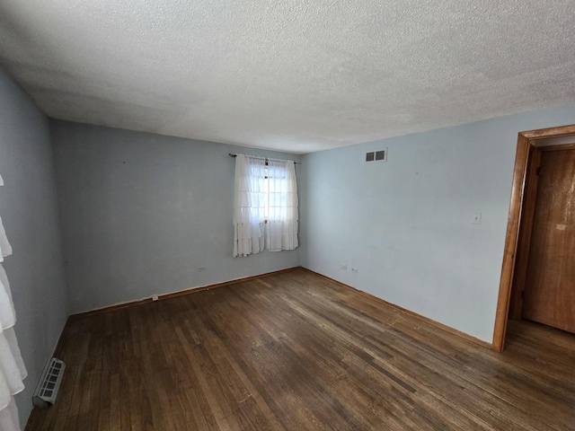 empty room with a textured ceiling and dark hardwood / wood-style floors