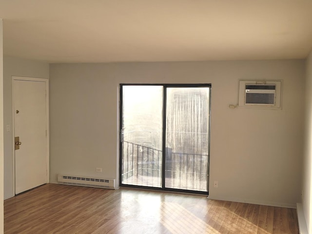 unfurnished room with a wall unit AC, a baseboard heating unit, a healthy amount of sunlight, and hardwood / wood-style flooring