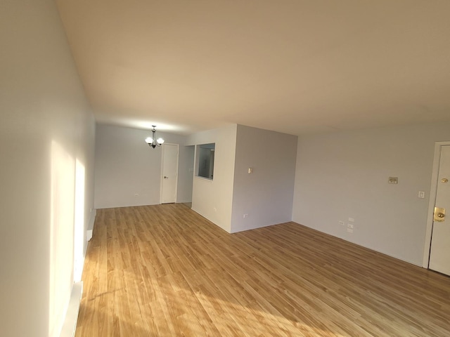 unfurnished living room featuring an inviting chandelier and light hardwood / wood-style flooring