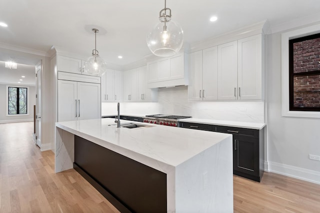 kitchen with sink, pendant lighting, an island with sink, and white cabinets