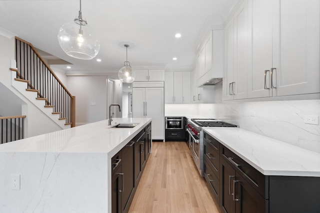 kitchen featuring sink, white cabinets, decorative light fixtures, a large island with sink, and high quality appliances