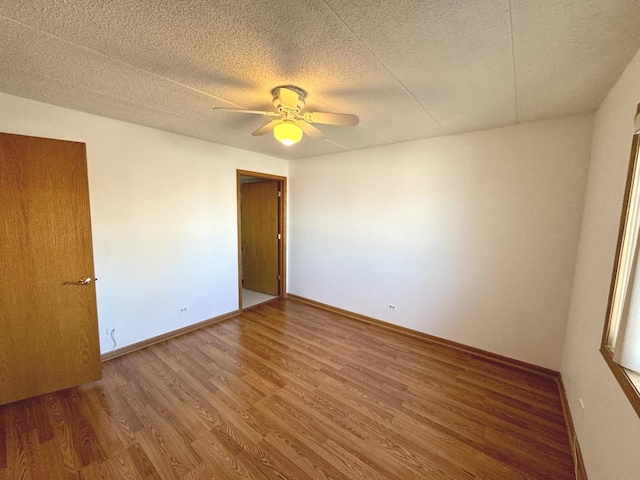 empty room with ceiling fan, a textured ceiling, and wood-type flooring