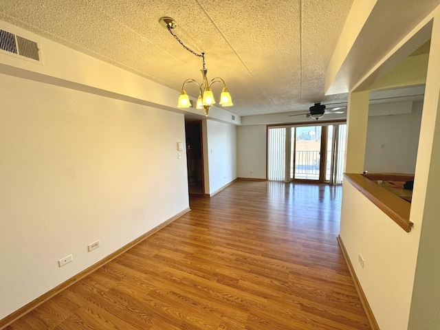 spare room featuring ceiling fan with notable chandelier, a textured ceiling, and hardwood / wood-style floors