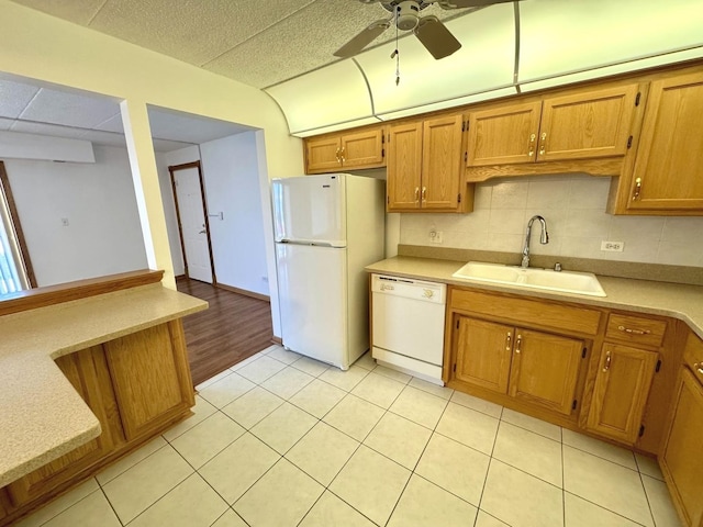 kitchen featuring white appliances, light tile patterned floors, ceiling fan, sink, and backsplash