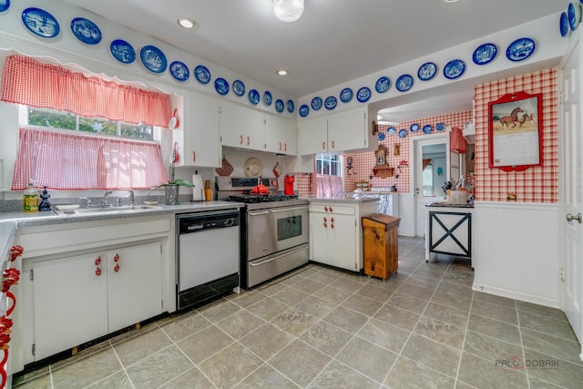 kitchen with sink, range with two ovens, dishwasher, and white cabinetry