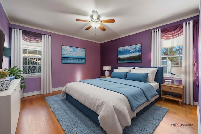 bedroom with ornamental molding, light wood-type flooring, ceiling fan, and multiple windows