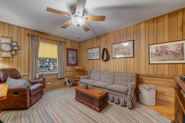 living room with ceiling fan and wood walls