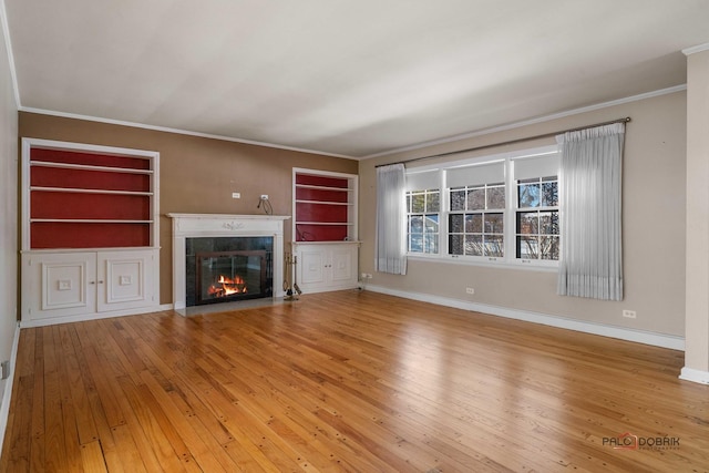 unfurnished living room featuring hardwood / wood-style floors, crown molding, and built in shelves