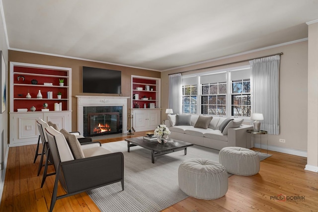 living room with hardwood / wood-style flooring, built in features, and ornamental molding