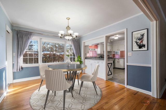 dining room with ornamental molding, light wood-type flooring, and a notable chandelier