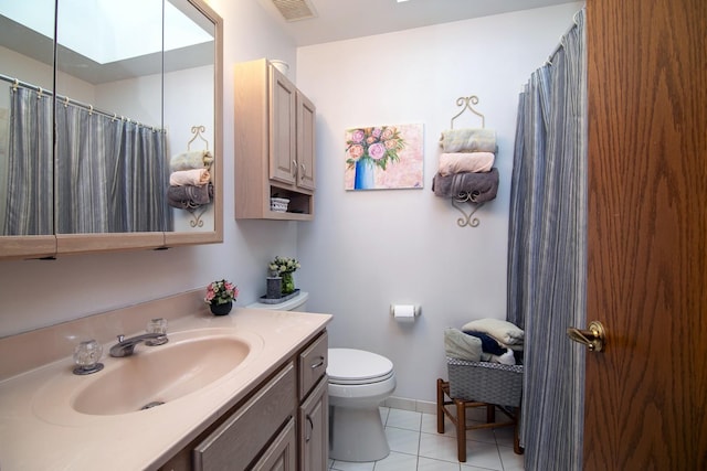 bathroom with a skylight, vanity, toilet, tile patterned floors, and a shower with shower curtain