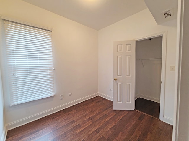 unfurnished bedroom with a closet, lofted ceiling, and dark hardwood / wood-style floors