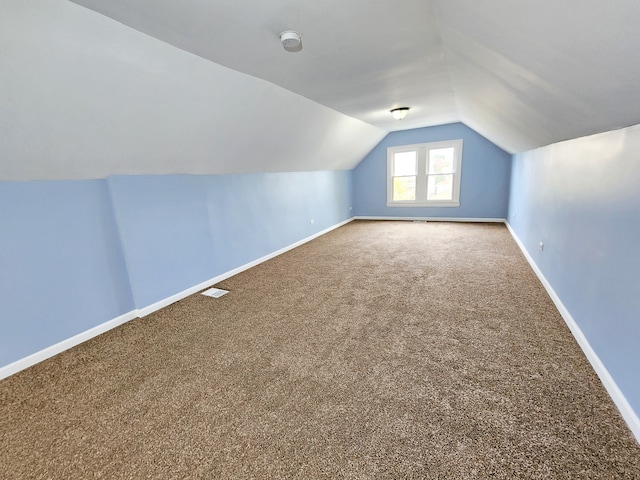 additional living space featuring lofted ceiling and carpet flooring